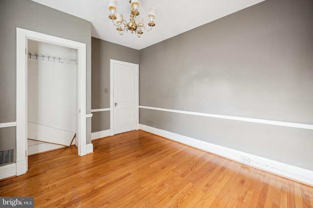 unfurnished dining area featuring a chandelier, light wood-style flooring, and baseboards