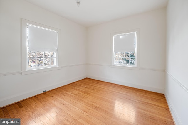 spare room with light wood-style flooring, baseboards, and a wealth of natural light