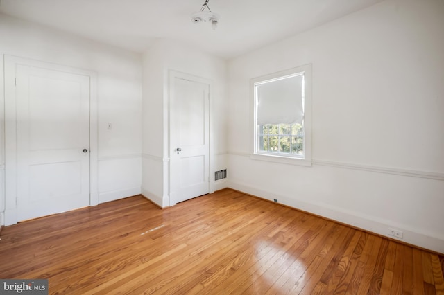 unfurnished room featuring light wood finished floors, visible vents, and baseboards