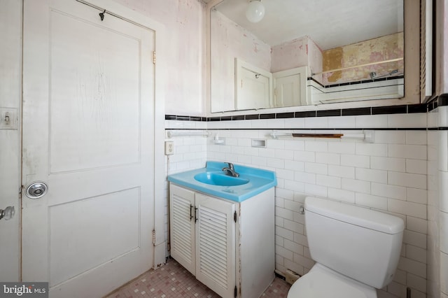 bathroom with toilet, vanity, and tile walls