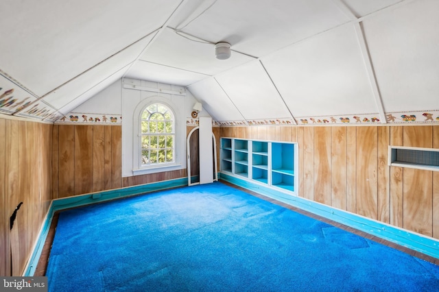 bonus room with wood walls, carpet, and vaulted ceiling