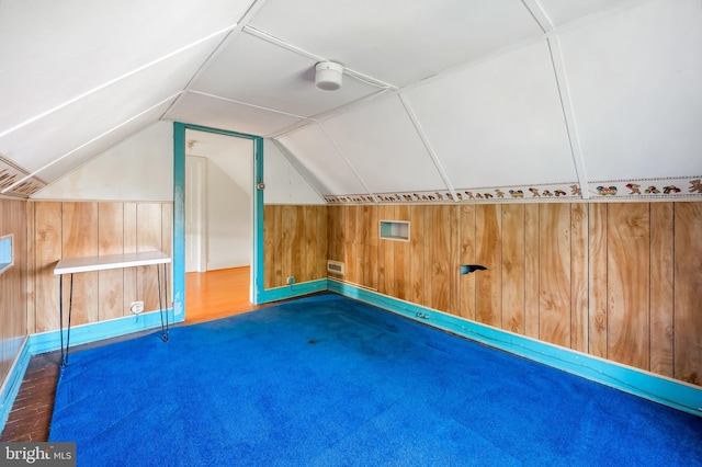 bonus room with lofted ceiling, visible vents, and wood walls