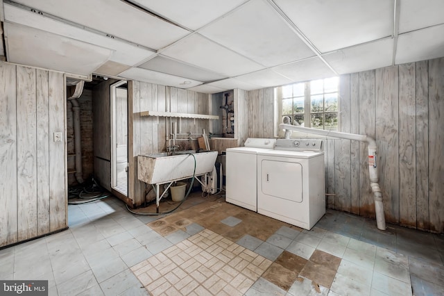 laundry area with laundry area, washer and clothes dryer, a sink, and wood walls