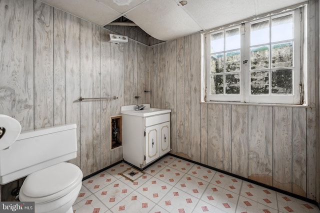 bathroom featuring wooden walls, vanity, toilet, and tile patterned floors