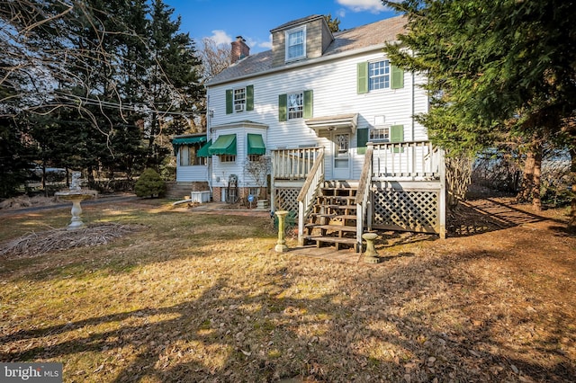 back of house with a deck, a lawn, and a chimney