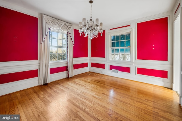 unfurnished dining area with a chandelier, wood finished floors, and visible vents