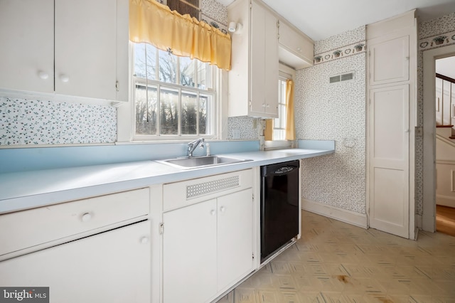 kitchen with a sink, white cabinets, black dishwasher, light countertops, and wallpapered walls