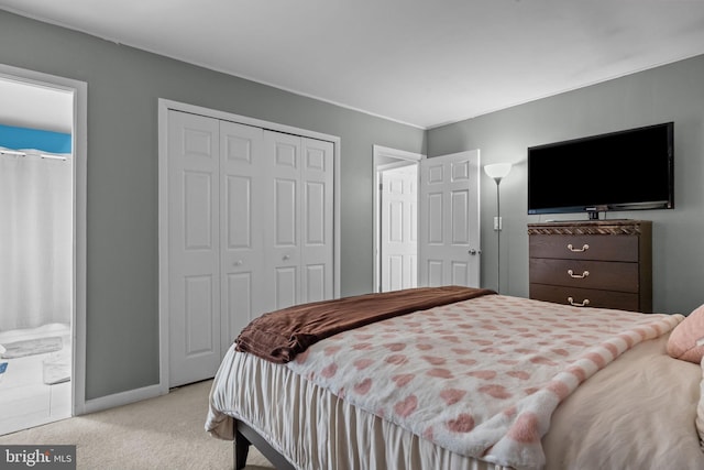 bedroom with ensuite bath and light carpet