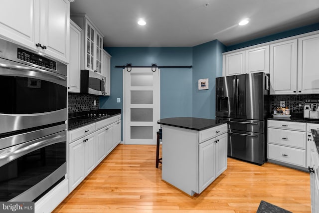 kitchen featuring a barn door, white cabinetry, appliances with stainless steel finishes, and light hardwood / wood-style floors