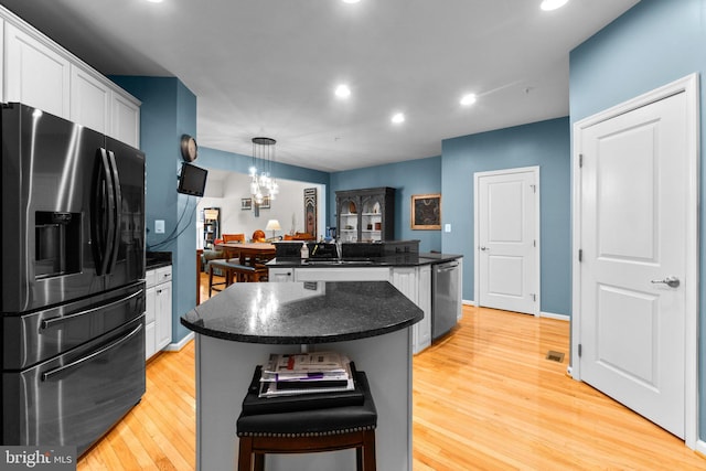 kitchen with a center island, light hardwood / wood-style flooring, hanging light fixtures, appliances with stainless steel finishes, and white cabinets