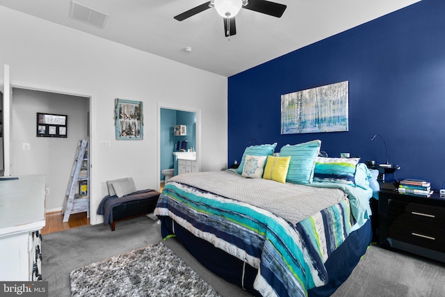 bedroom with ensuite bathroom, light carpet, and ceiling fan