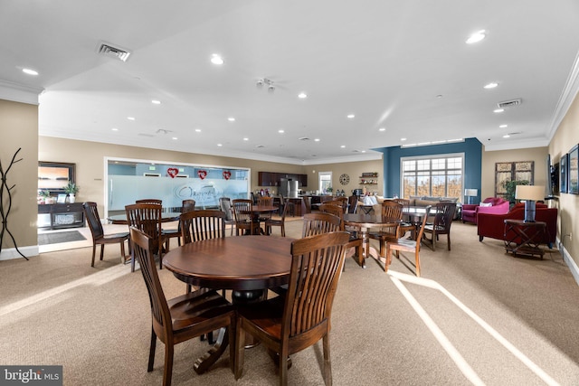 dining room featuring ornamental molding and light carpet