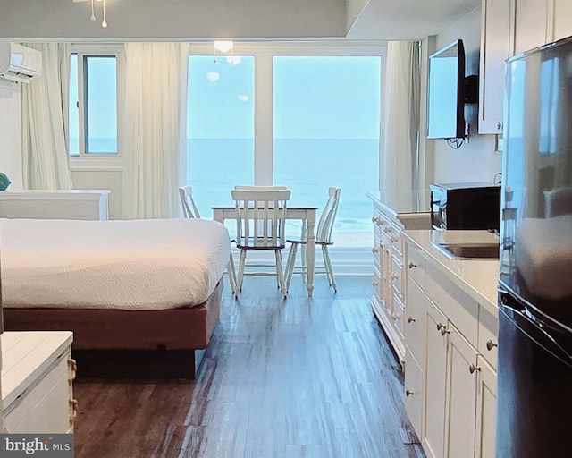 bedroom with fridge, dark hardwood / wood-style floors, and a wall mounted AC