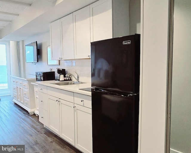 kitchen featuring white cabinetry, black refrigerator, sink, and dark hardwood / wood-style floors