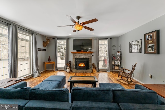 living room with a stone fireplace, a healthy amount of sunlight, and light wood-type flooring