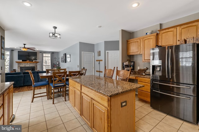 kitchen featuring dark stone counters, stainless steel fridge with ice dispenser, and light tile patterned floors