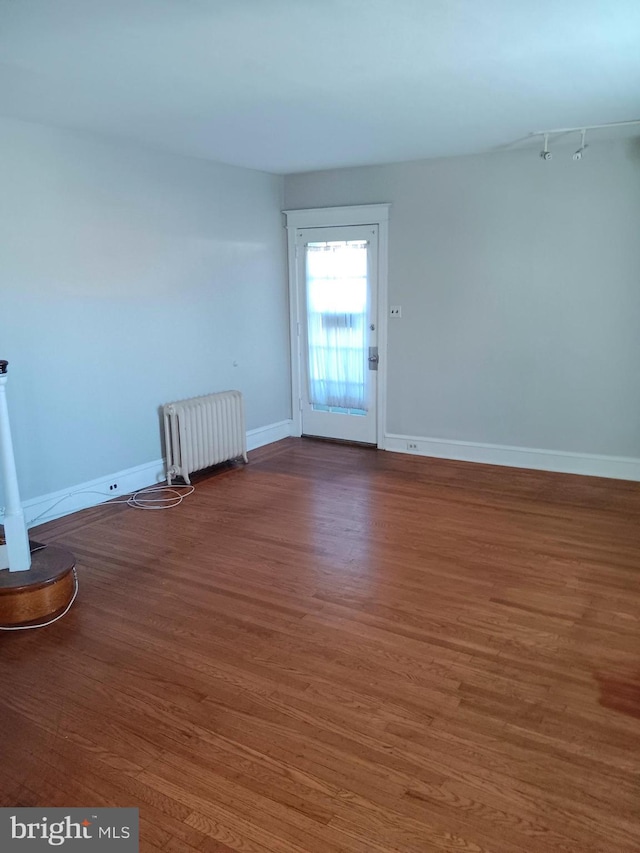 spare room with dark hardwood / wood-style floors and radiator