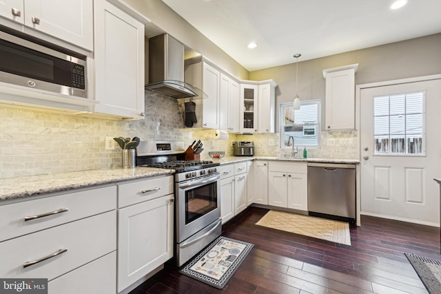 kitchen featuring white cabinets, wall chimney exhaust hood, pendant lighting, and stainless steel appliances