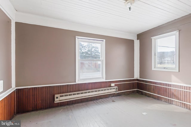 unfurnished room featuring a baseboard radiator and wooden walls