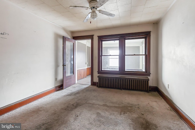 empty room featuring carpet floors, radiator, and ceiling fan