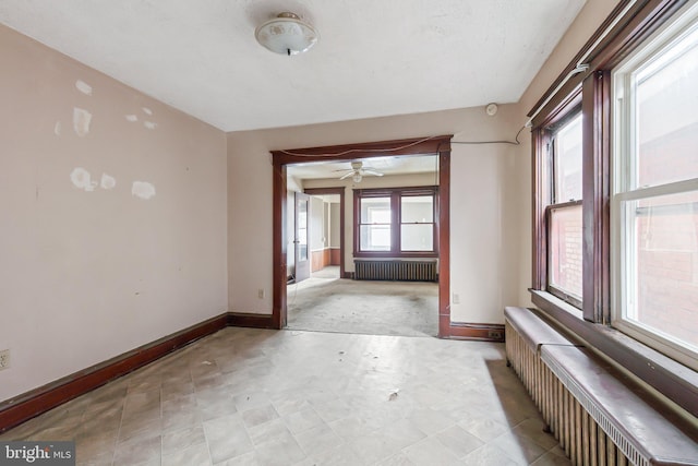 unfurnished room with radiator and ceiling fan