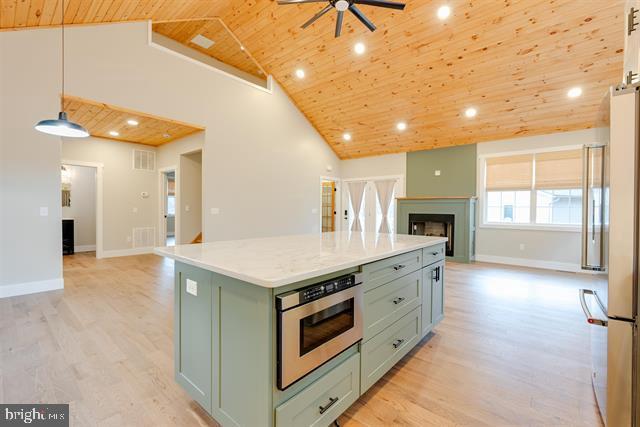 kitchen featuring wood ceiling, high end refrigerator, hanging light fixtures, a kitchen island, and light hardwood / wood-style floors