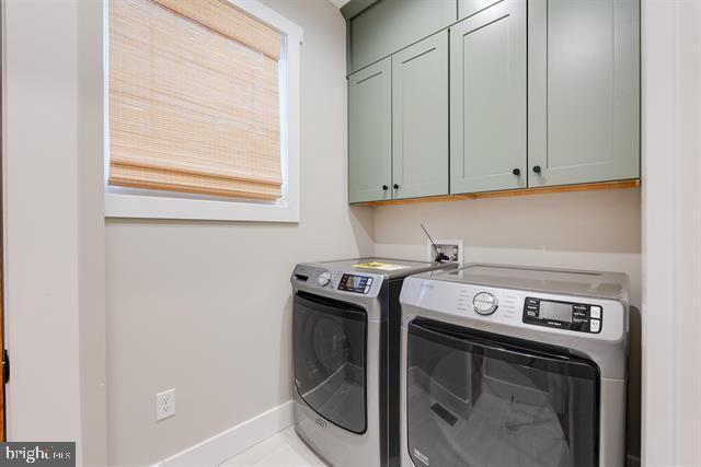 laundry area with independent washer and dryer and cabinets