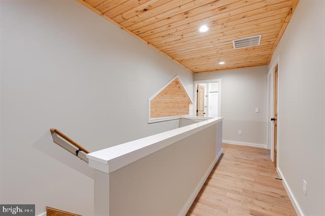 hallway featuring light hardwood / wood-style floors and wooden ceiling