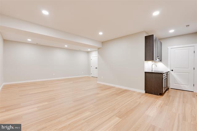 basement featuring light hardwood / wood-style floors and sink