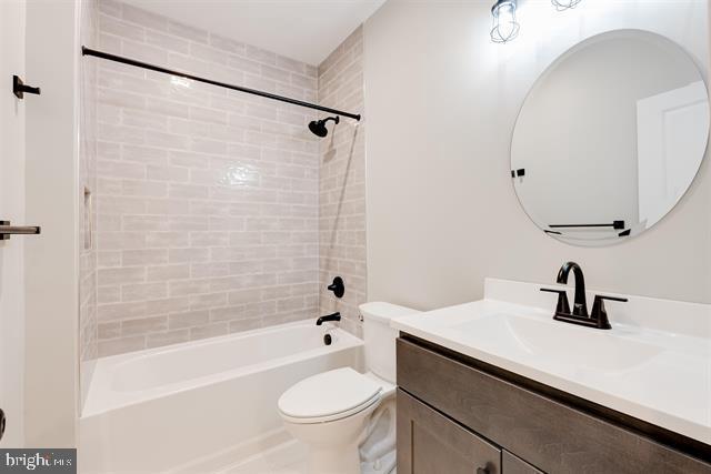 full bathroom featuring tiled shower / bath combo, vanity, and toilet