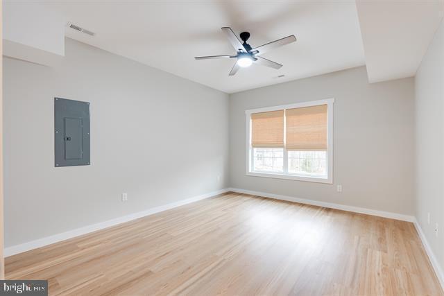 spare room featuring electric panel, light hardwood / wood-style floors, and ceiling fan