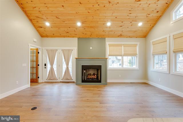 unfurnished living room with high vaulted ceiling, wooden ceiling, and light wood-type flooring