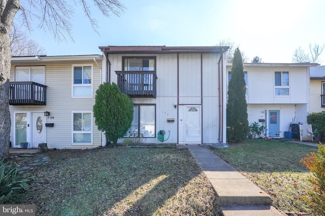 view of property featuring a front lawn and a balcony