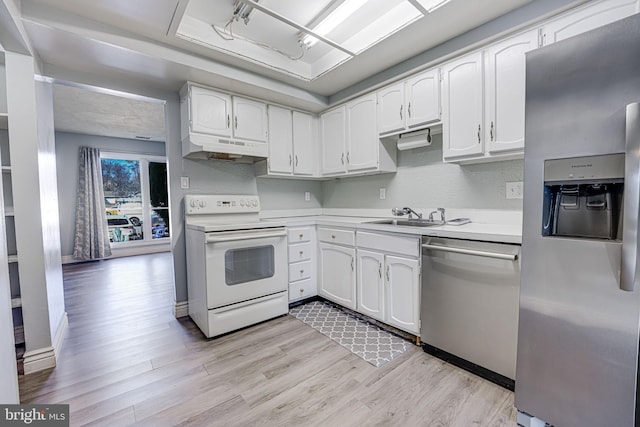 kitchen with sink, light hardwood / wood-style flooring, appliances with stainless steel finishes, white cabinetry, and a raised ceiling