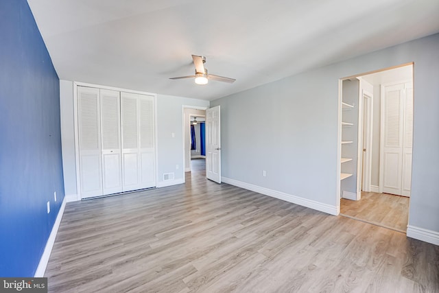 unfurnished bedroom with ensuite bathroom, a closet, ceiling fan, and light wood-type flooring