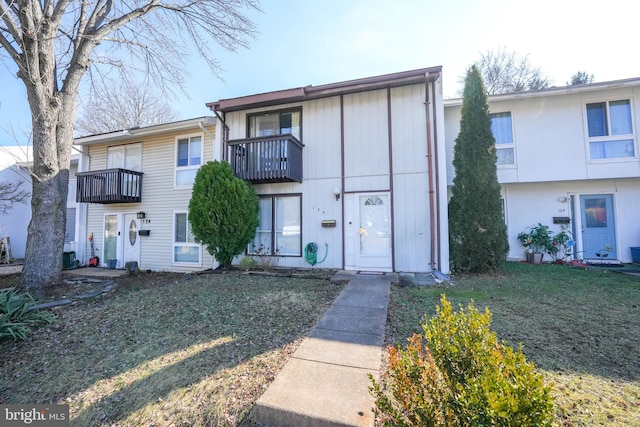 townhome / multi-family property featuring a balcony and a front yard