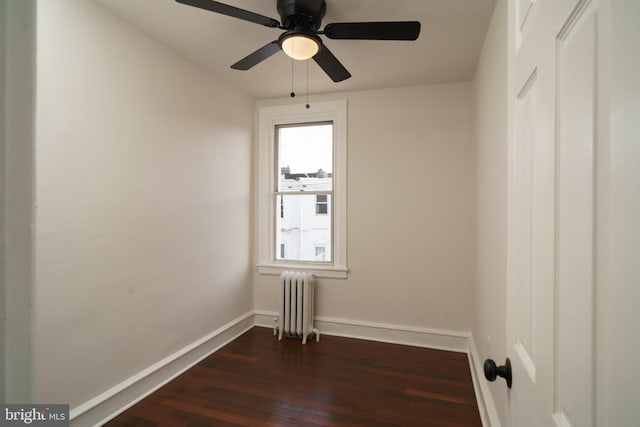 spare room with dark wood-style floors, radiator, baseboards, and a ceiling fan