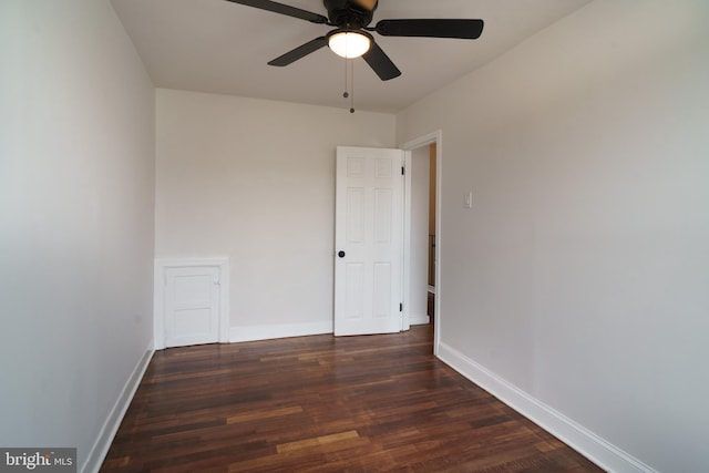 spare room featuring dark wood-style floors, a ceiling fan, and baseboards