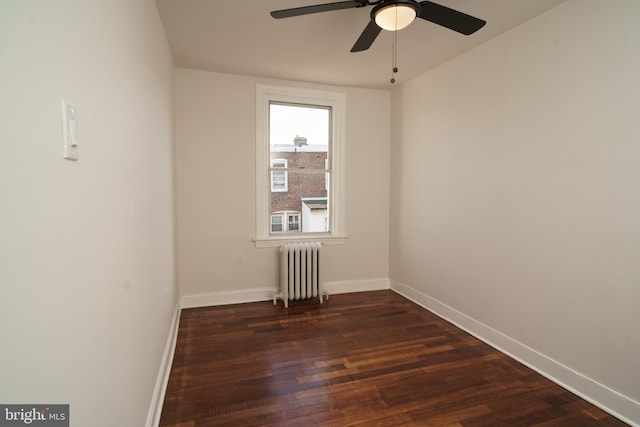 spare room with dark wood-style flooring, baseboards, ceiling fan, and radiator heating unit