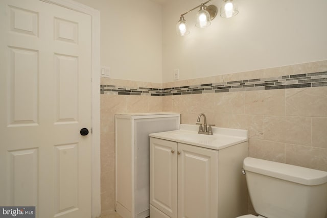 bathroom featuring toilet, vanity, and tile walls