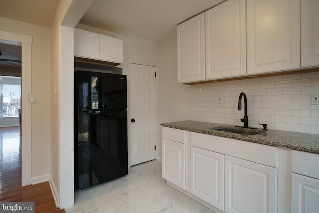 kitchen with freestanding refrigerator, white cabinetry, and a sink