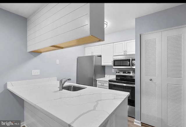 kitchen with sink, appliances with stainless steel finishes, white cabinetry, light stone countertops, and kitchen peninsula