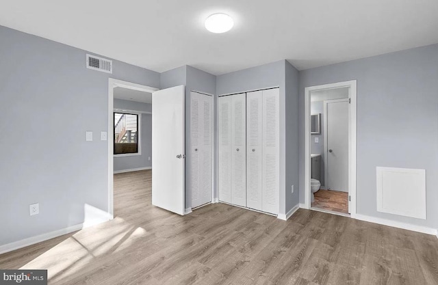 unfurnished bedroom featuring ensuite bath and light wood-type flooring