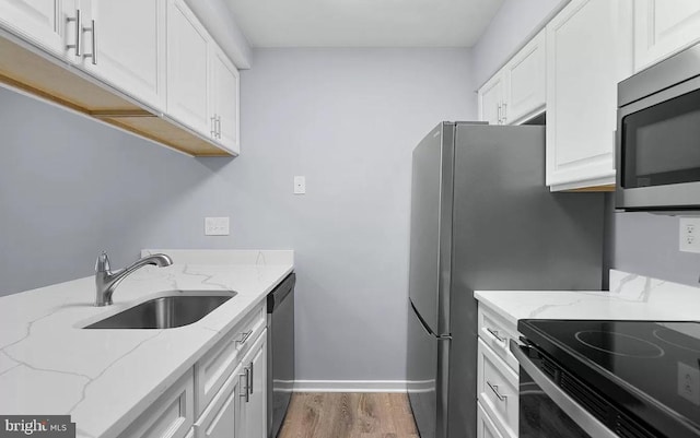 kitchen with stainless steel appliances, light stone countertops, and sink