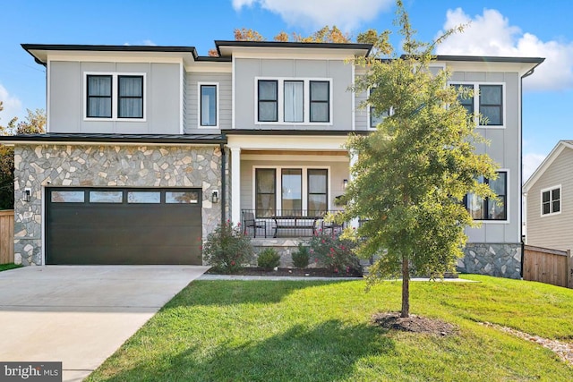 view of front of property with a garage, a front yard, and covered porch