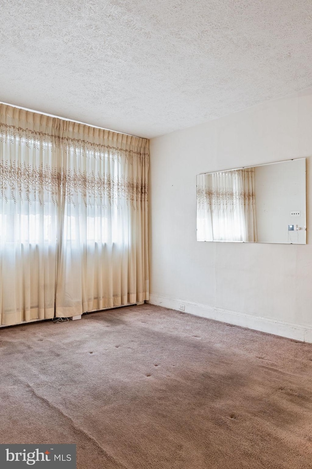 empty room with carpet floors, plenty of natural light, and a textured ceiling