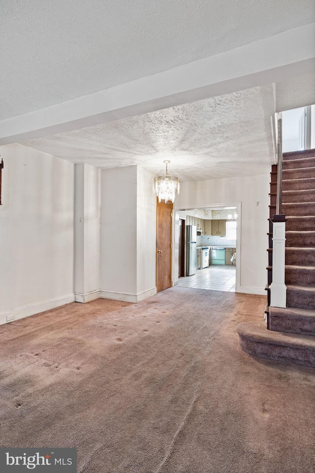 unfurnished living room with an inviting chandelier, carpet, and a textured ceiling