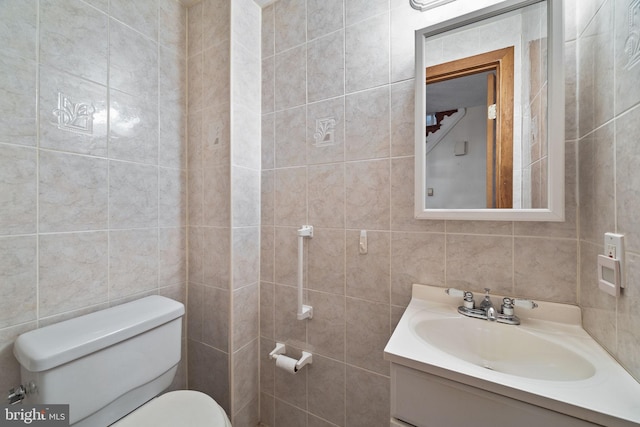 bathroom with vanity, toilet, and tile walls