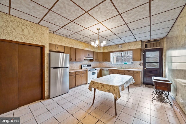 kitchen with sink, a chandelier, light tile patterned floors, stainless steel appliances, and decorative backsplash