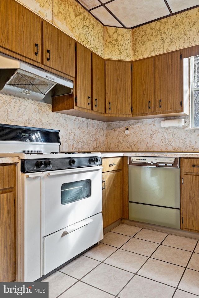 kitchen with tasteful backsplash, light tile patterned flooring, stainless steel dishwasher, and white gas range oven